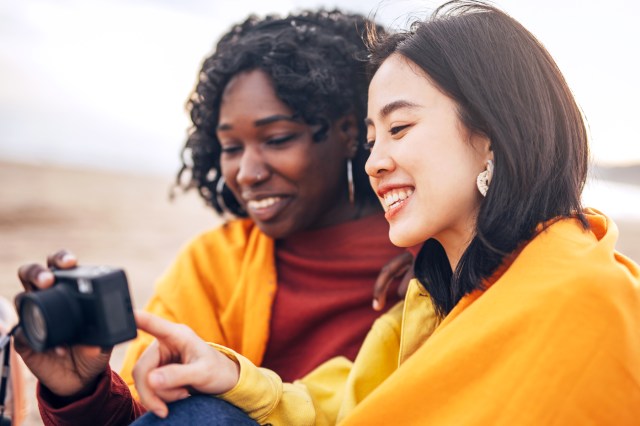 two friends smiling, looking at pictures on a camera