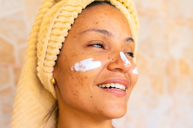 Closeup of a woman with a towel on her head and cream on her face