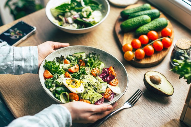 Woman mixing superfood salad ingredients in kitchen