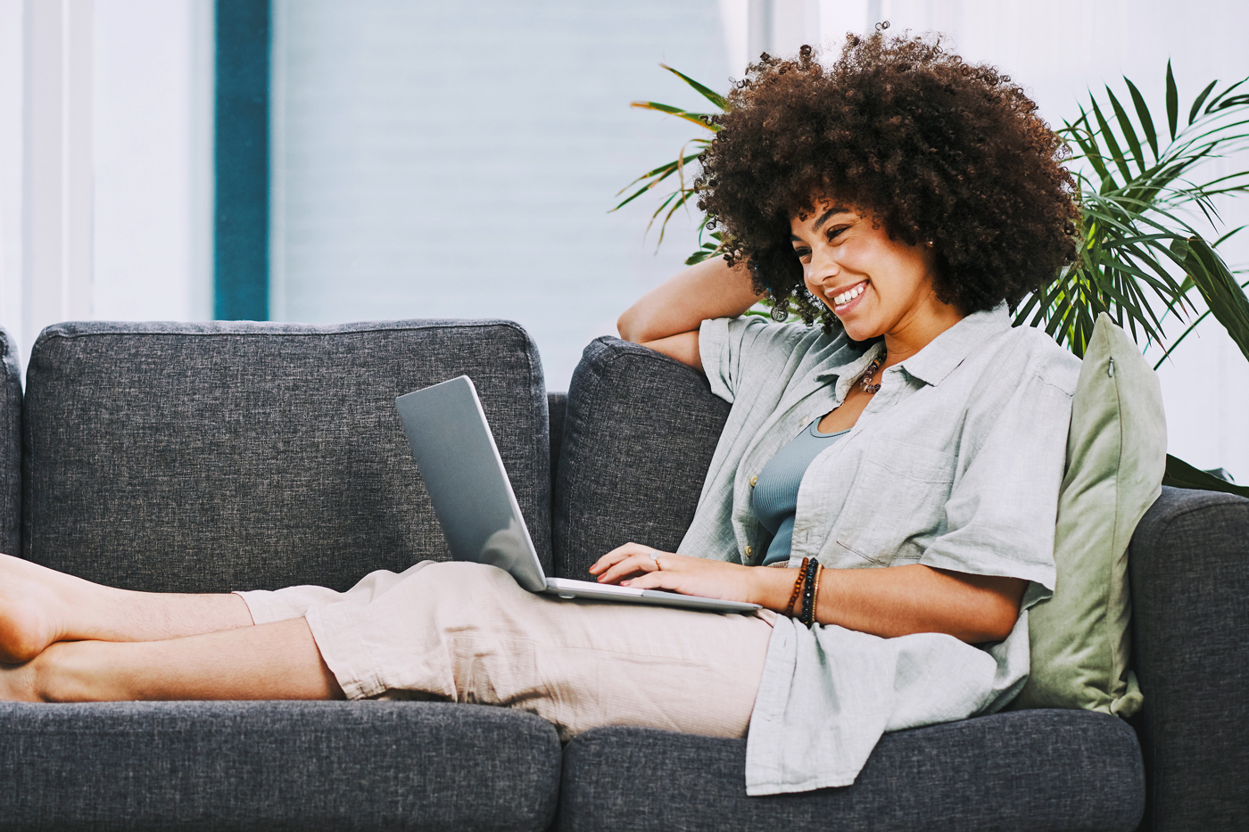 Woman sitting on couch with laptop, using computer