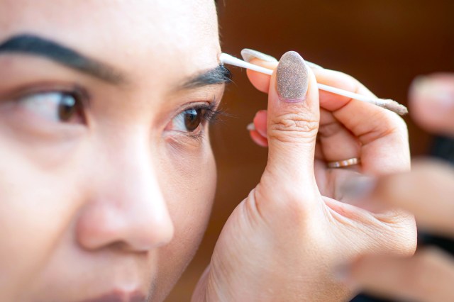 Close-up of a person using a cotton swab on their eyebrow