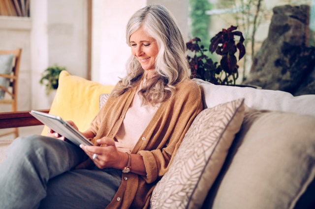 Smiling mature woman using tablet on her couch