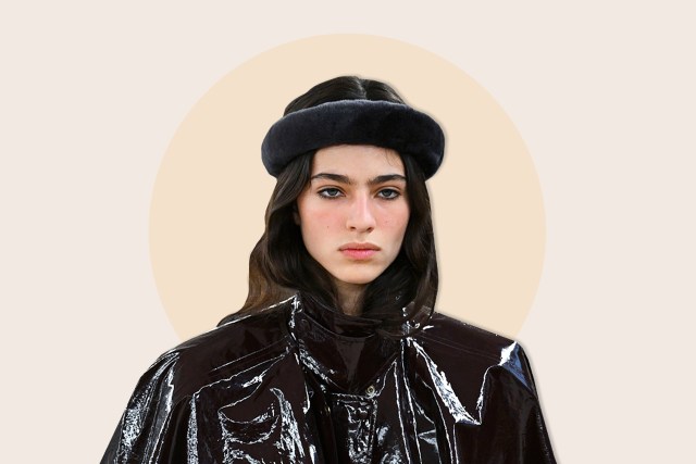 Model wearing black hat and shiny dark jacket