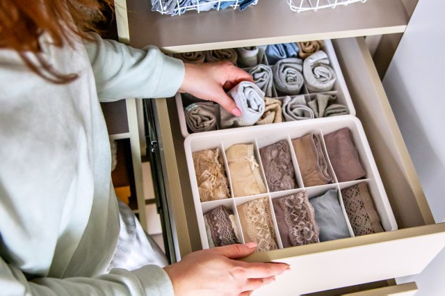 Top view, female hands, open drawer with clothes organizer