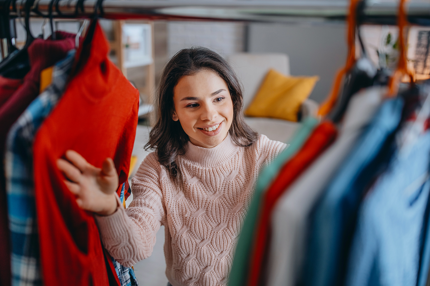 Young woman looking through clothes in her closet