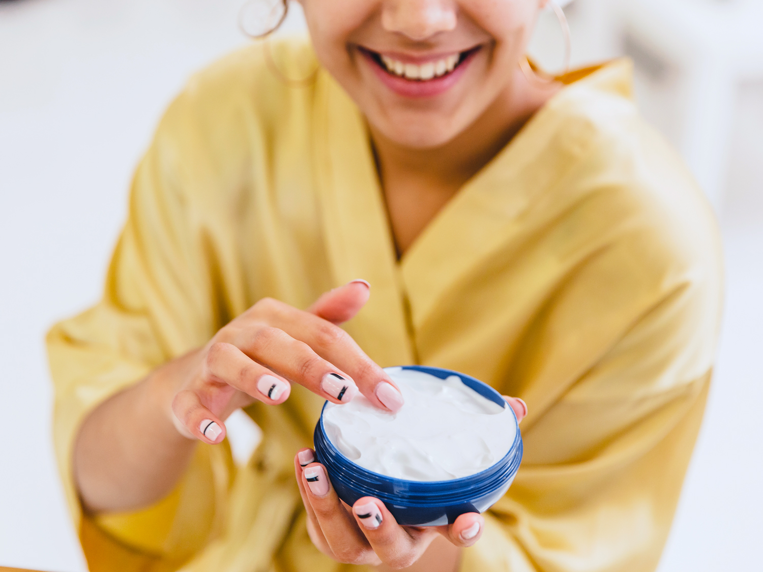 Cropped view of woman touching cream in container