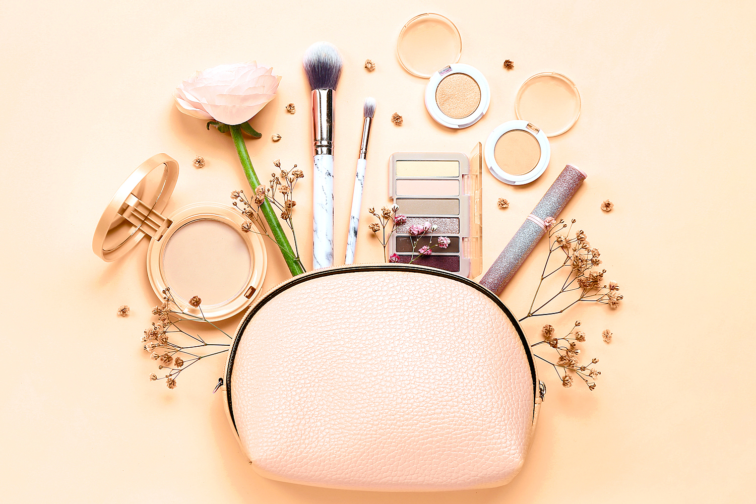 Still life of make up bag with cosmetics and flowers