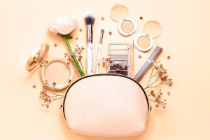 Still life of make up bag with cosmetics and flowers