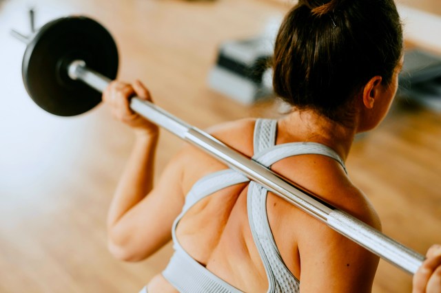 Back view of woman lifting weight bar