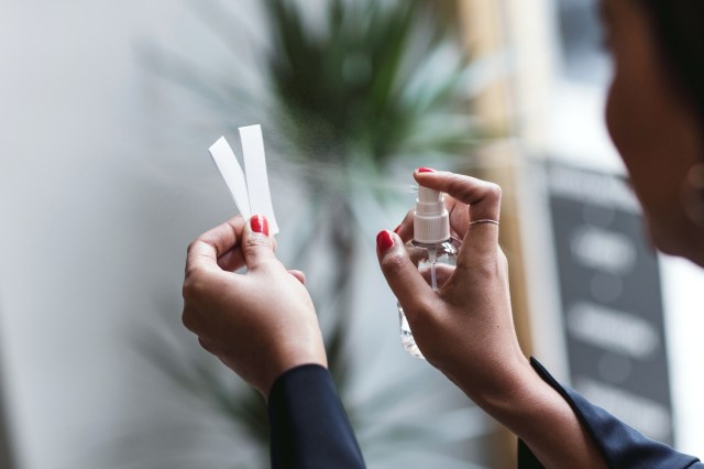 Woman spraying perfume on a tester strip