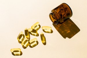 Capsules and a glass bottle on a beige background