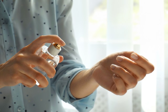 Close up of woman spraying perfume on wrist