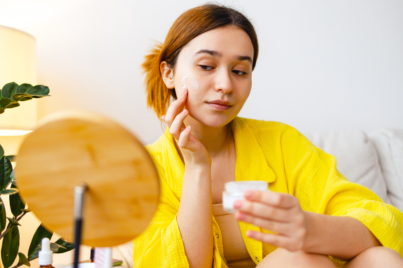 woman applying skin care in fron tof the mirror