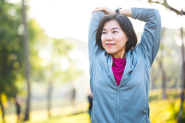 Woman outside stretching her arms above her head