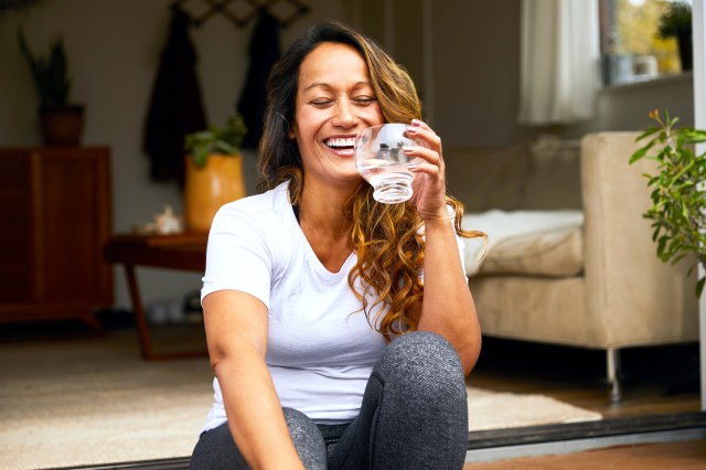 Laughing mature woman drinking water on her patio