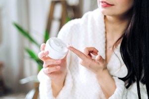 Woman in bathrobe using lotion