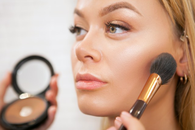 Close up of woman applying blush to her cheek