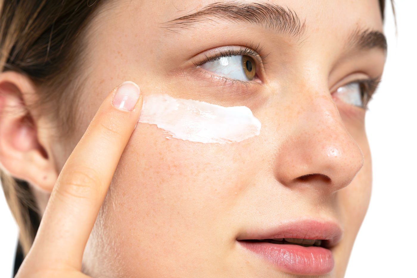 Woman putting eye cream on her face