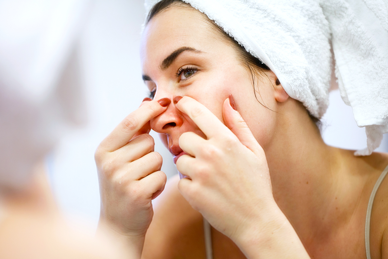 woman popping a pimple on her nose