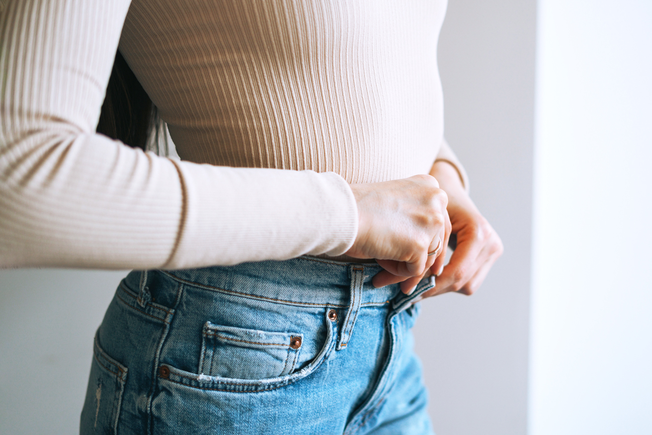 Close up of woman buttoning jeans